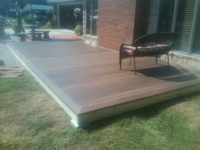 New wood deck and wicker chair beside a brick house in Portland