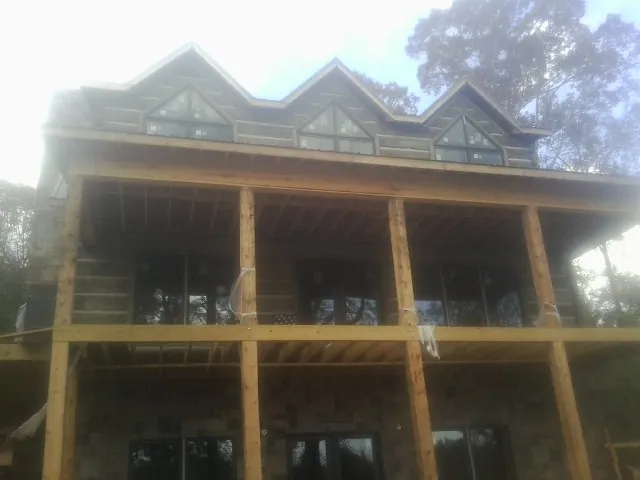 Dormers and porch framing on a large log home under construction — Roof Coating work by our crew in Portland